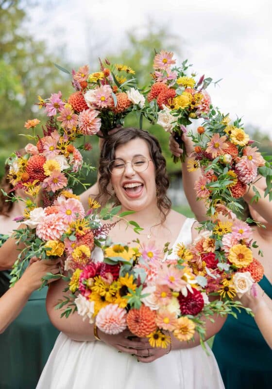 a bride smiling with bridesmaids bouquets all around her, at Cana vineyards