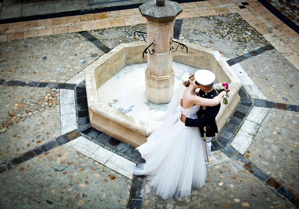 Bride and groom in military uniform kiss at fountain, Williamsburg Winery