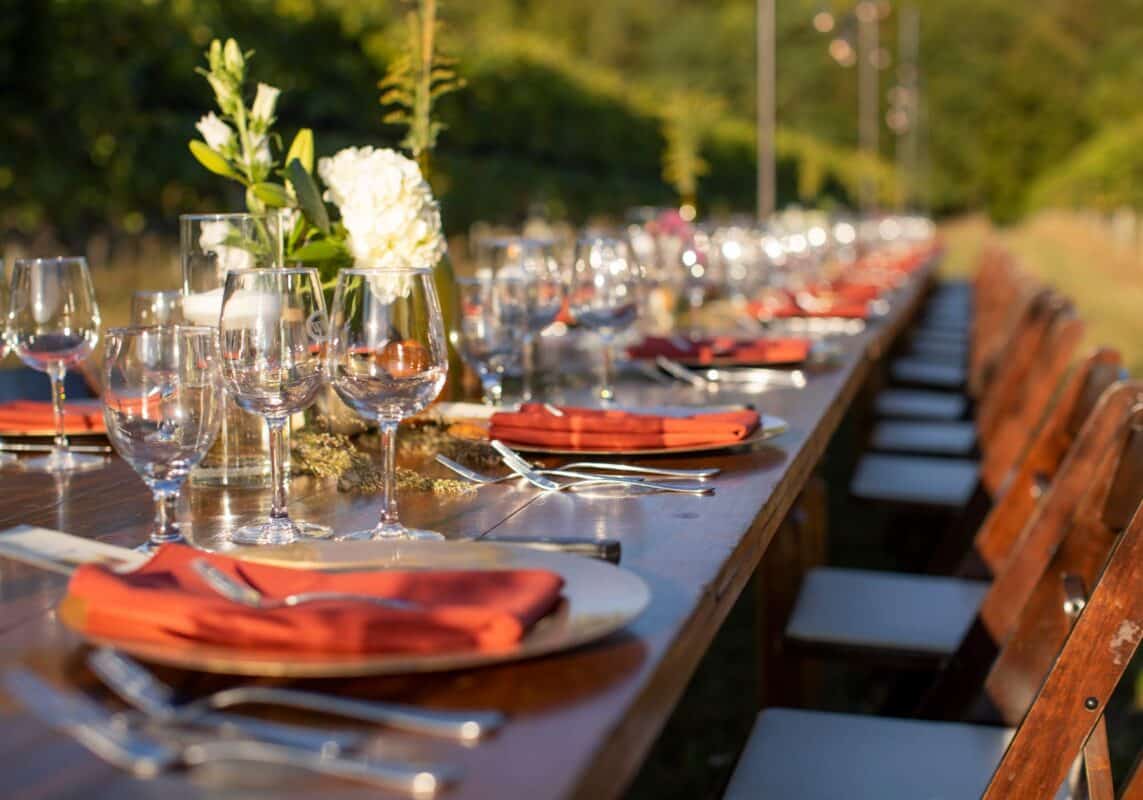 Outdoor dinner in the field at Williamsburg Winery. Beautiful wooden table and chairs among grapevines set for a wine paired feast.