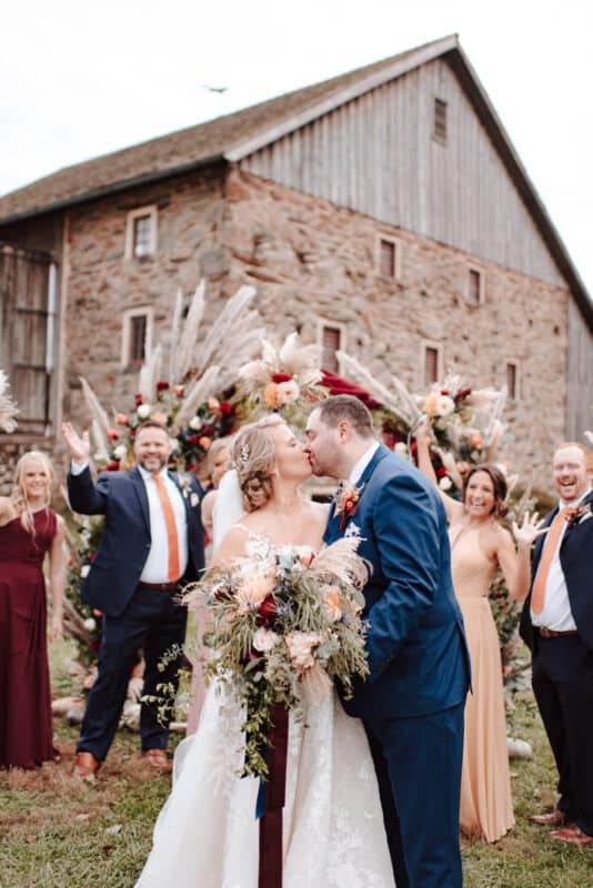 Bride and groom kiss at wedding barn