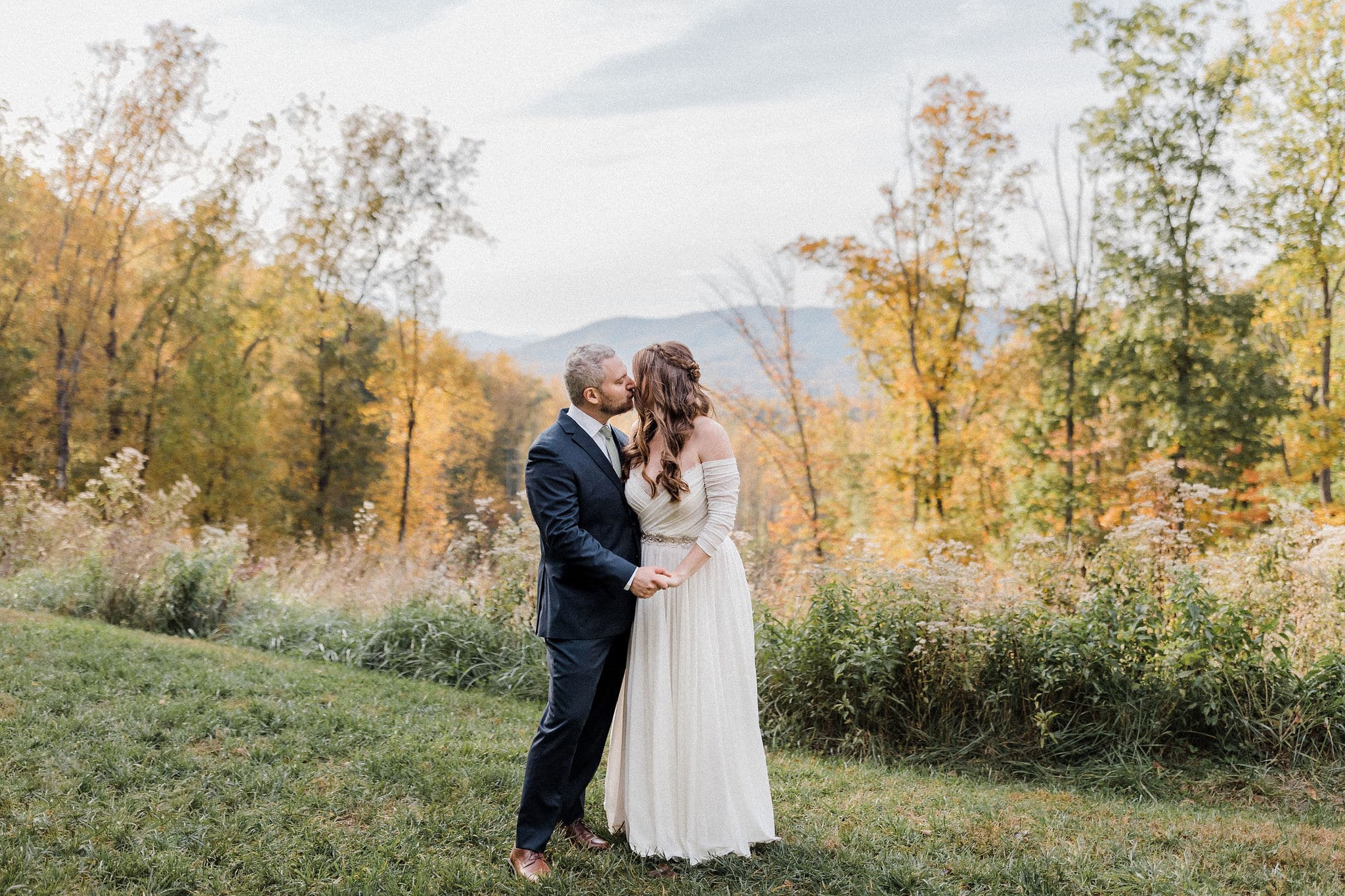 Fall colors, bride and groom kissing with blue ridge mountains in background