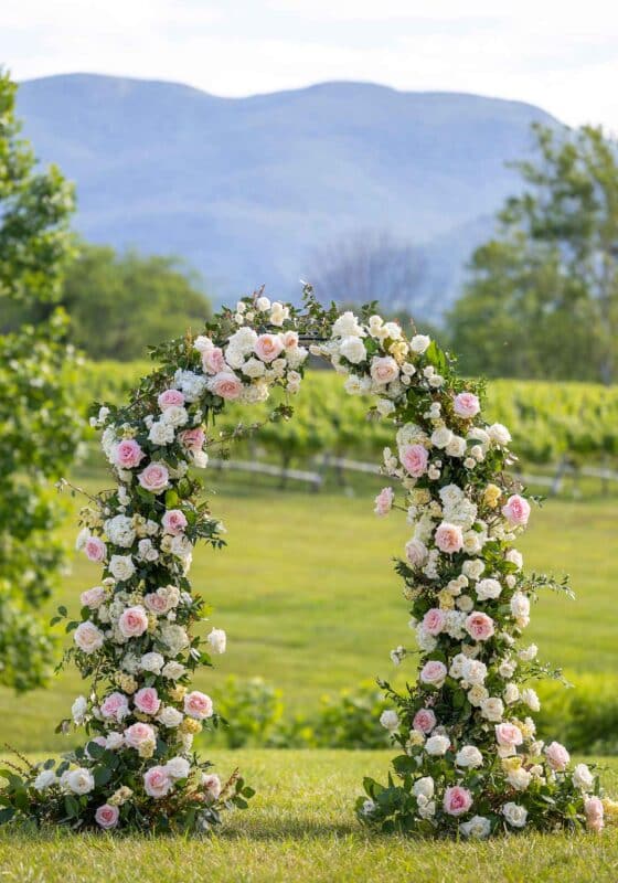 flower arch of pale pink and white roses with mountain views and vines in background at Veritas