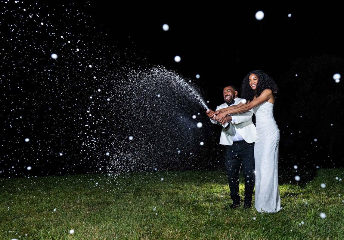 night shot of bride and groom spraying Veritas sparkling wine