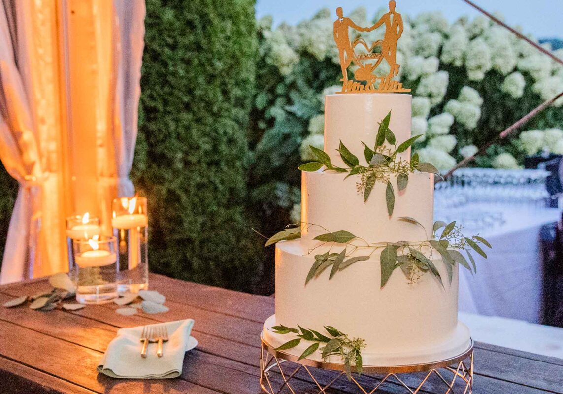 mr and mr wedding cake topper on 3 tier white wedding cake with sprigs of greenery