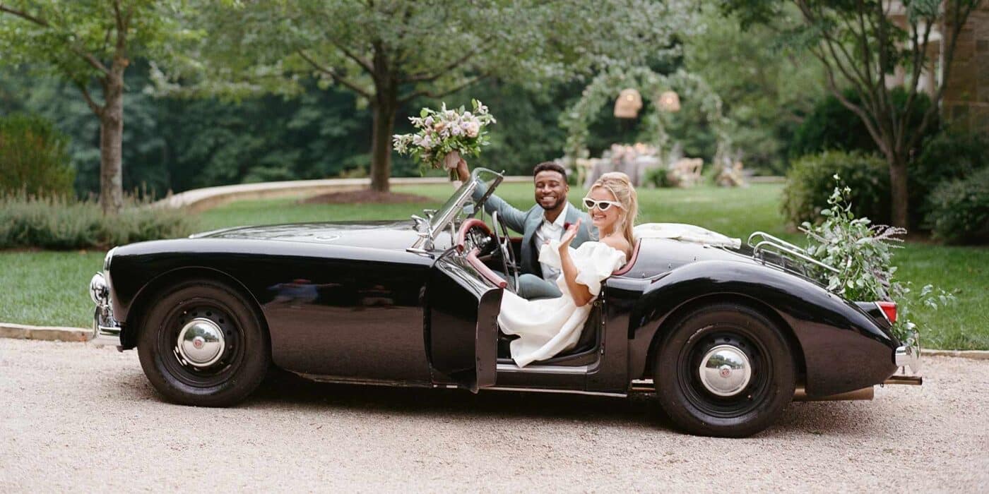 Black vintage sports car with wedding couple